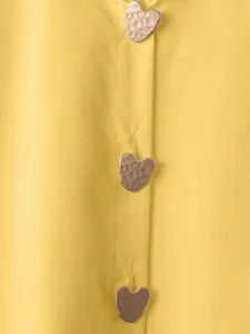 Dettaglio di camicia retrò gialla con bottoni a cuore in metallo martellato e bella caduta.