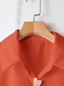 Primo piano del colletto della camicia casual arancione con dettagli di bottoni a cuore.