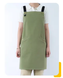 Cotton canvas green work apron detail featuring adjustable black straps and metal buttons.