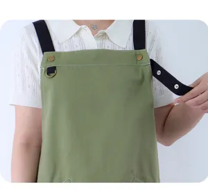 Cotton work apron with adjustable black straps, metal buttons, and D-ring for kitchen use.