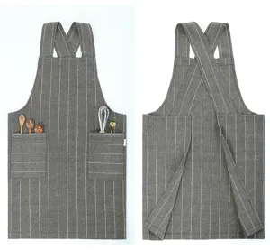 Grey striped cotton linen apron detail showcasing cross-back straps and front utility pockets.