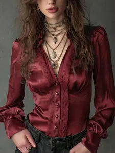 Burgundy satin long sleeve blouse detail, featuring deep V-neck and delicate lace trim.