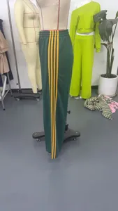 Detail shot of green track pants with yellow side stripes, high waist and elastic design.