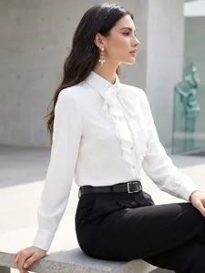 Detalles de la blusa blanca de manga larga con lazo, volantes y cuello solapa.