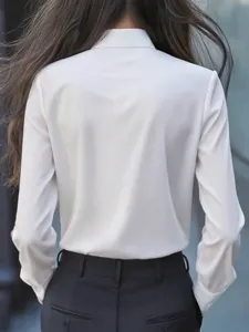 Elegante blusa blanca de manga larga para mujer con cuello solapa y pantalones negros.