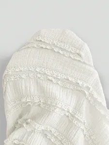 White long sleeve dress fabric detail featuring delicate lace tiers and soft summer texture.