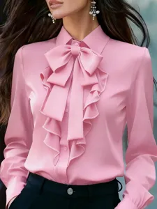 Vista detallada de la elegante blusa rosa de manga larga con cuello de lazo y volantes chic.