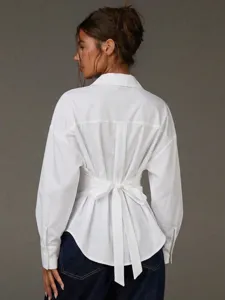 Vista posteriore di una camicia bianca a maniche lunghe con elegante nastro in vita.