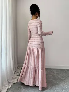 Pink textured long sleeve dress detail showcasing ruffled fabric and elegant back silhouette.