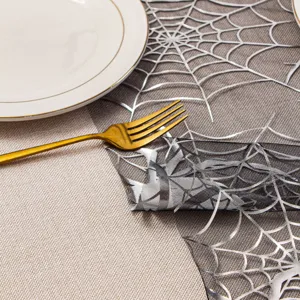 Detalle del camino de mesa plateado con telaraña de encaje para decoración de fiesta.