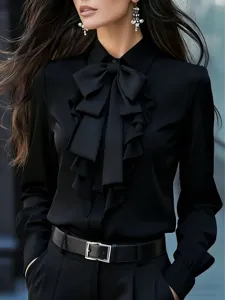 Elegante camisa negra de manga larga con cuello de lazo y finos detalles de volantes al frente.