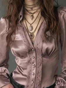 Close-up detail shot of satin V-neck long sleeve blouse with delicate lace trim.