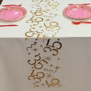 Détail du chemin de table en résille blanche avec imprimé or 35 et étoiles pour fête.