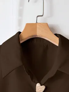 Vista dettagliata del colletto della camicia casual marrone scuro con bottone a cuore.