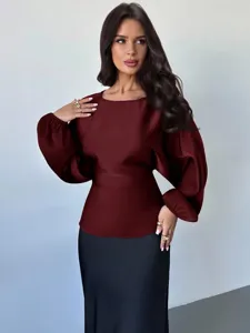 Close-up of burgundy long-sleeve blouse with lantern sleeves and fitted waist detail.