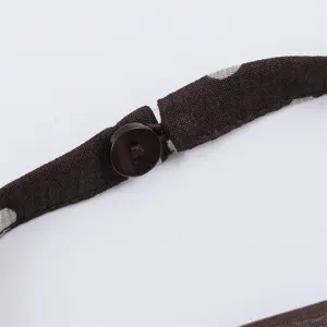 Detail view of brown polka dot halter top strap with button closure, stylish and elegant.
