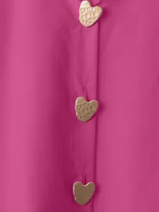 Primo piano dettagliato di camicia fucsia con bottoni dorati a cuore con finitura martellata.