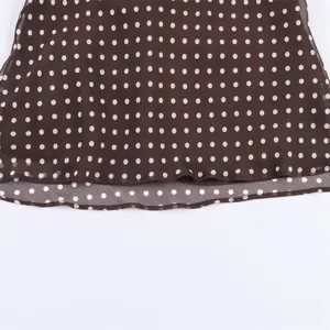 Close-up of women brown polka dot chiffon top hem, lightweight fabric detail view for style.