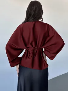 Back view detail of women solid burgundy long sleeve blouse with tied waist design.