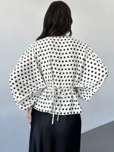 Back view detail of women's black and white polka dot blouse with long batwing sleeves and tie waist.