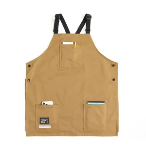 Detailed view of durable khaki canvas barista work apron with multi pockets and cross straps.