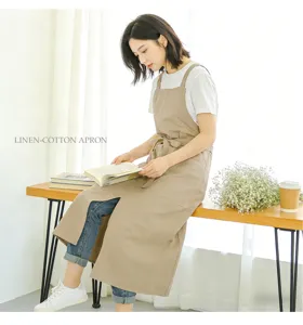 Detailed view of khaki linen cotton apron with cross back straps, side pockets and waist tie.