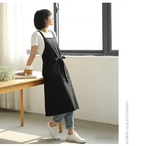 Black linen cotton apron with cross back straps and pockets for cooking or cafe work.