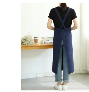 Detailed back view shot of a dark blue cotton linen cross back apron in minimalist cafe scene setting.
