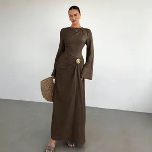 Κομψό καφέ γυναικείο μακρύ φόρεμα με μακριά μανίκια, λεπτές πιέτες και μεταλλική αγκράφα.