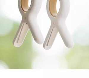 Primer plano detallado de un clip de plástico blanco grande para ropa de cama con muelle.