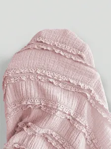 Close-up detail of pink textured fabric with delicate lace ruffle tiers for women dress.