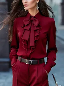 Detalle de la elegante blusa burdeos con volantes delanteros y un bonito lazo en el cuello.