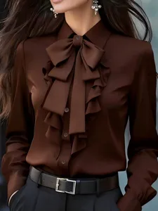 Vista detallada de la blusa marrón de manga larga para mujer con cuello de lazo y volantes.