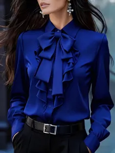 Blusa azul real de manga larga con elegante lazo en el cuello y volantes frontales.