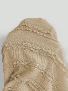 Close-up detail of a beige layered ruffled dress featuring delicate lace trim and textured fabric.