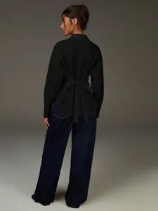 Vista dettagliata della camicia nera a maniche lunghe con elegante fiocco e colletto.