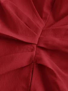 Close-up of red textured fabric with stylish crossover wrap and ruching detail for top.