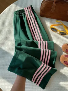 Close-up detail of vintage green casual pants with pink side stripes, Y2K retro style.