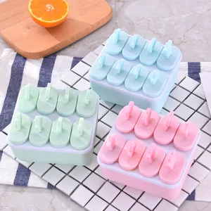 Gros plan de moules à esquimaux colorés avec bâtonnets, idéaux pour les crèmes glacées maison.