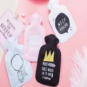 Detailed view of colorful cute hot water bags with printed text and cozy flat lay design.