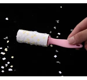 Detail view of the portable lint roller with pink handle removing dust and paper bits easily.