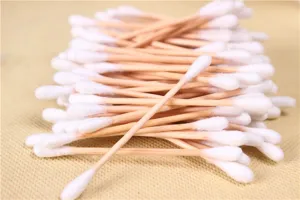 Close-up detail of disposable double-headed wooden cotton swabs with soft white tips.