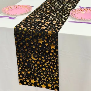 Detailansicht von schwarzem Tischläufer mit goldenem Mond und Sternen für Partiedekoration.