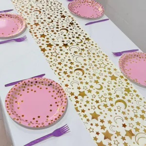 Tischläufer mit goldenen Sternen und Monden, rosa Teller und Gabeln für Partydekoration.