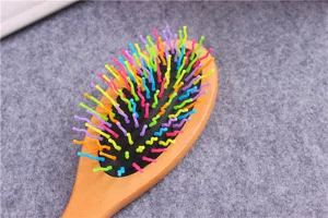 Close-up of wooden hairbrush with colorful wavy bristles, ergonomic handle detail texture.