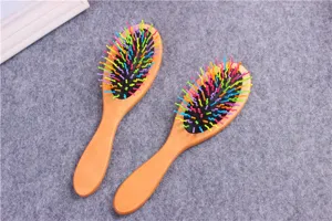 Wooden hair brush detail showing colorful bristles and cushion base on grey background.