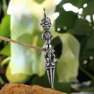Vintage metal dorje pendant detail, retro style Buddhist vajra amulet necklace close up view.