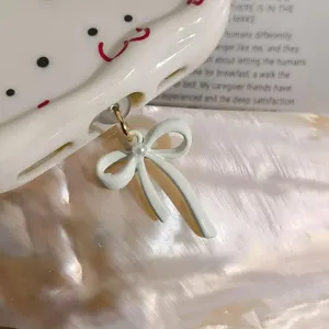 Chic white bow phone dust plug with pearl detail, cute charging port charm for women.