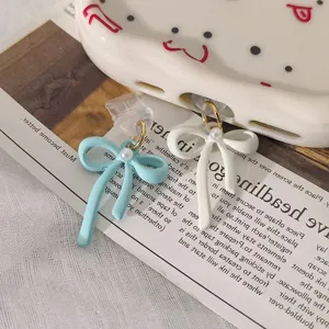 Detailed close-up of cute double bow phone charm and dust plug with elegant pearl decoration.