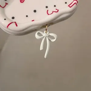 White bow phone dust plug charm, charging port accessory, cute smartphone decoration detail